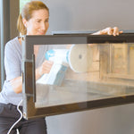 Frau reinigt mit dem Livington SteamBuddy die verrußte Glasscheibe eines Kamins
