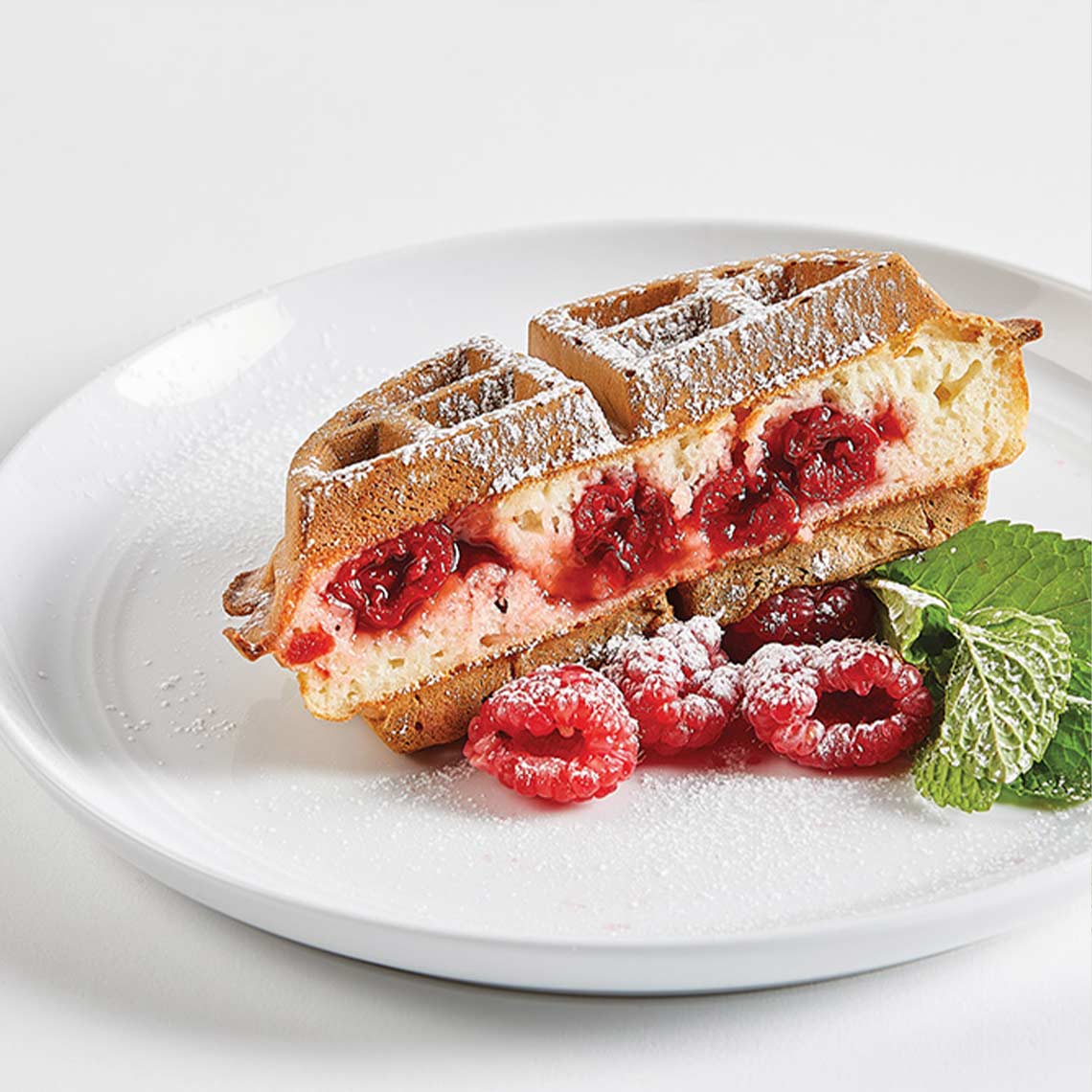 PowerXL Waffle Star – Waffelsandwich mit Frischkäse-Kirschfüllung, dekoriert mit Himbeeren und Minze.