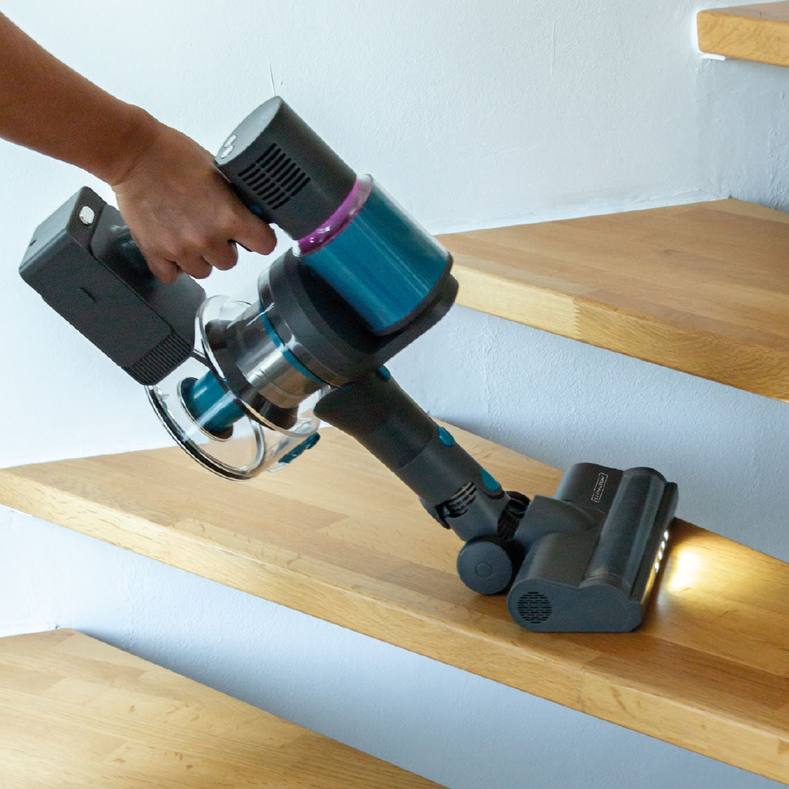 Ein Akkusauger mit LED-Bürste reinigt komfortabel eine Holztreppe.