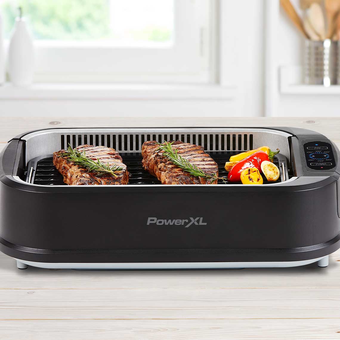 PowerXL Smokeless Grill – zwei Rindersteaks mit Rosmarin und Grillgemüse auf gerillter Grillplatte.