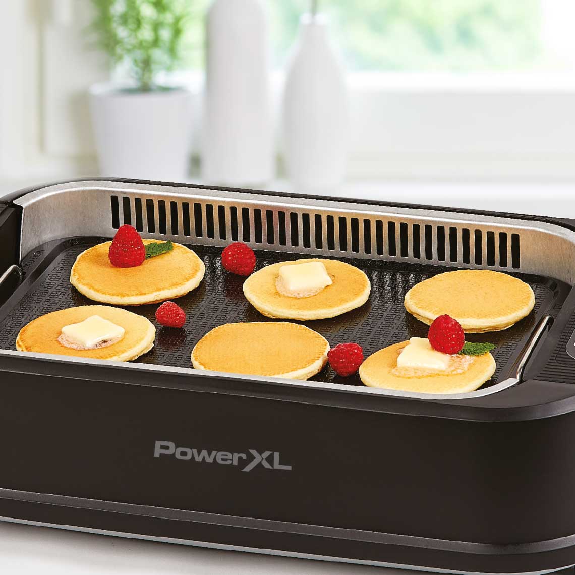 PowerXL Smokeless Grill – sechs Pancakes mit Butter und Himbeeren auf glatter Grillplatte.