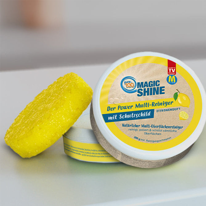 Magic Shine: Eine Person poliert mit gelbem Schwamm ein silbernes Gefäß – Besteck liegt im Hintergrund auf schwarzem Glanz.