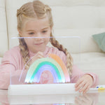 Mädchen zeichnet einen Regenbogen auf einem beleuchteten Mini-Leuchtboard