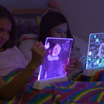 Zwei Mädchen zeichnen im Bett auf beleuchteten Mini-Leuchtboards mit buntem Lichteffekt.