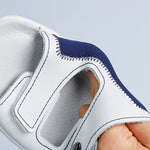 Detailaufnahme eines weißen Handschuhs mit blauer Naht, offener Fingerpartie und verstärktem Material.