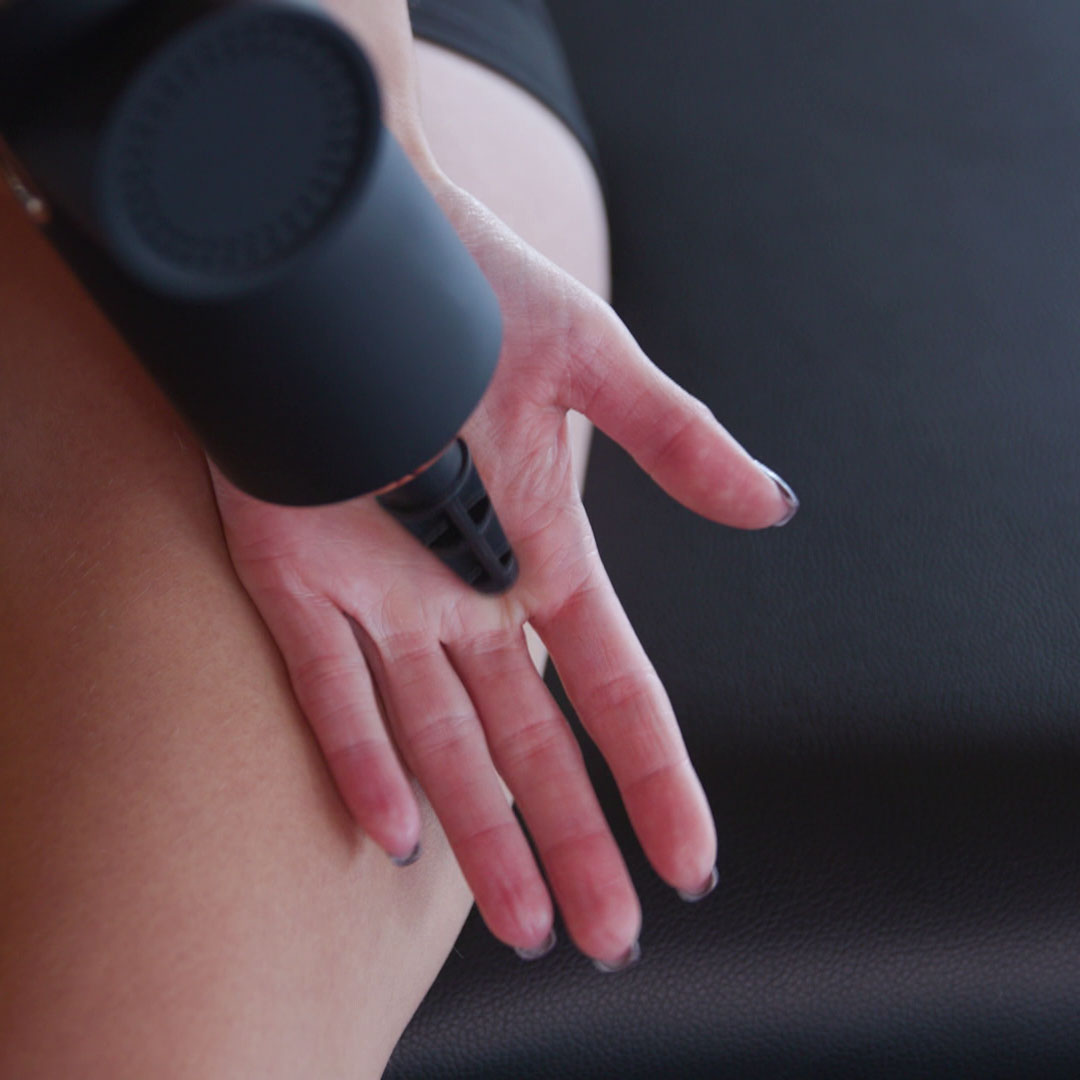 Anwendung einer Massagepistole im Bereich der Hand