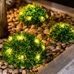Grüne Deko-Kugeln mit LED-Lichtern für stimmungsvolle Garten- oder Terrassengestaltung.