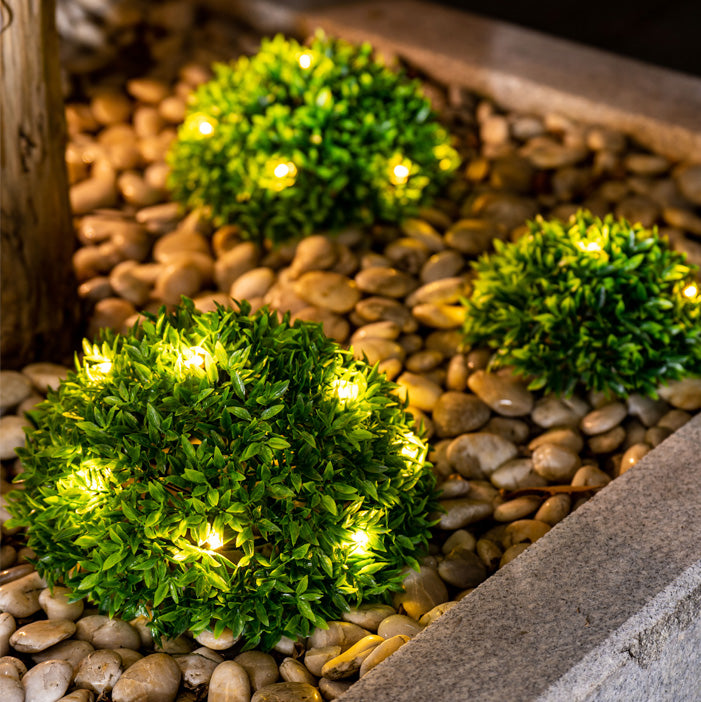 Grüne Deko-Kugeln mit LED-Lichtern für stimmungsvolle Garten- oder Terrassengestaltung.