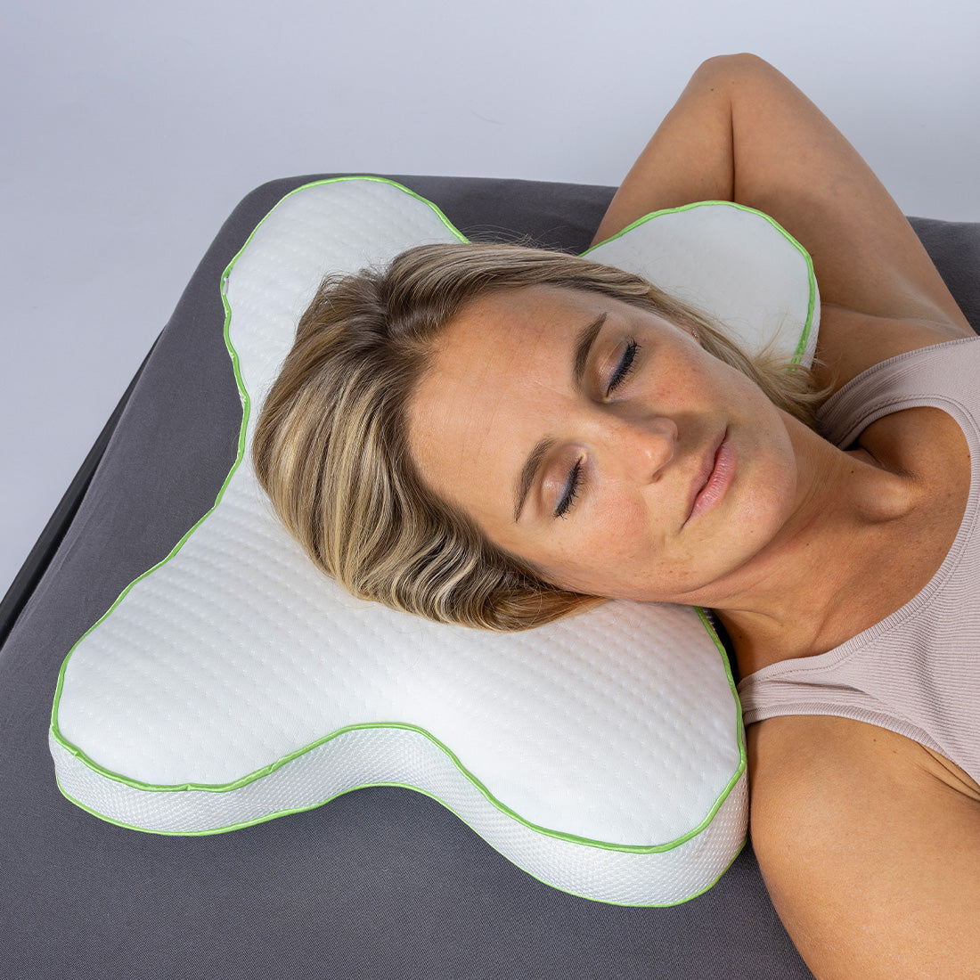 Frau liegt seitlich auf ergonomischem Schmetterlingskissen mit weißem Bezug und grünem Rand.