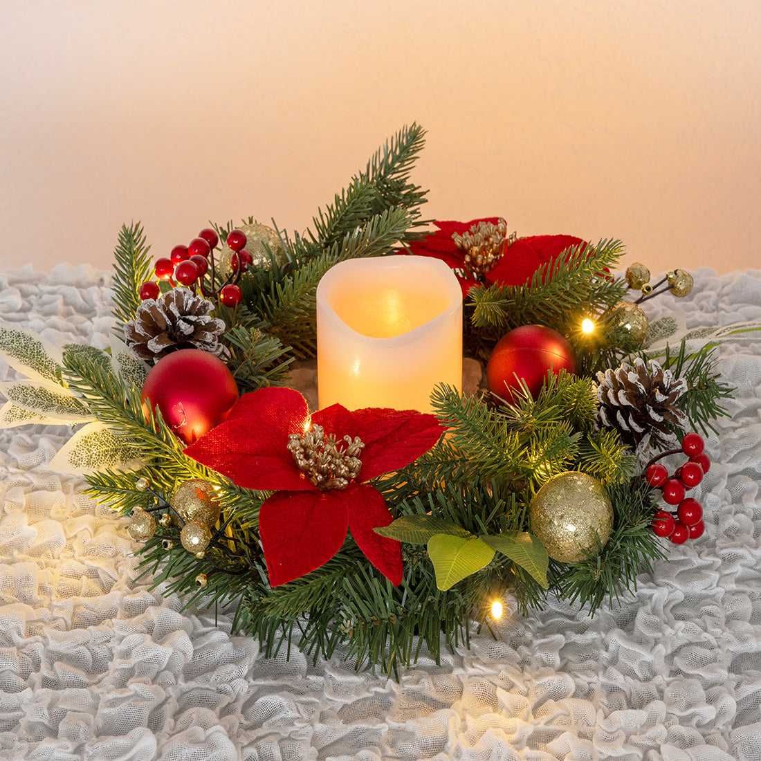 Weihnachtskranz mit LED-Kerze in der Mitte, roten Blüten, Tannenzweigen, Kugeln, Zapfen und Beeren dekoriert.
