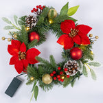 Beleuchteter Weihnachtskranz mit roten Blüten, Tannenzweigen, Kugeln, Zapfen und Batteriefach.