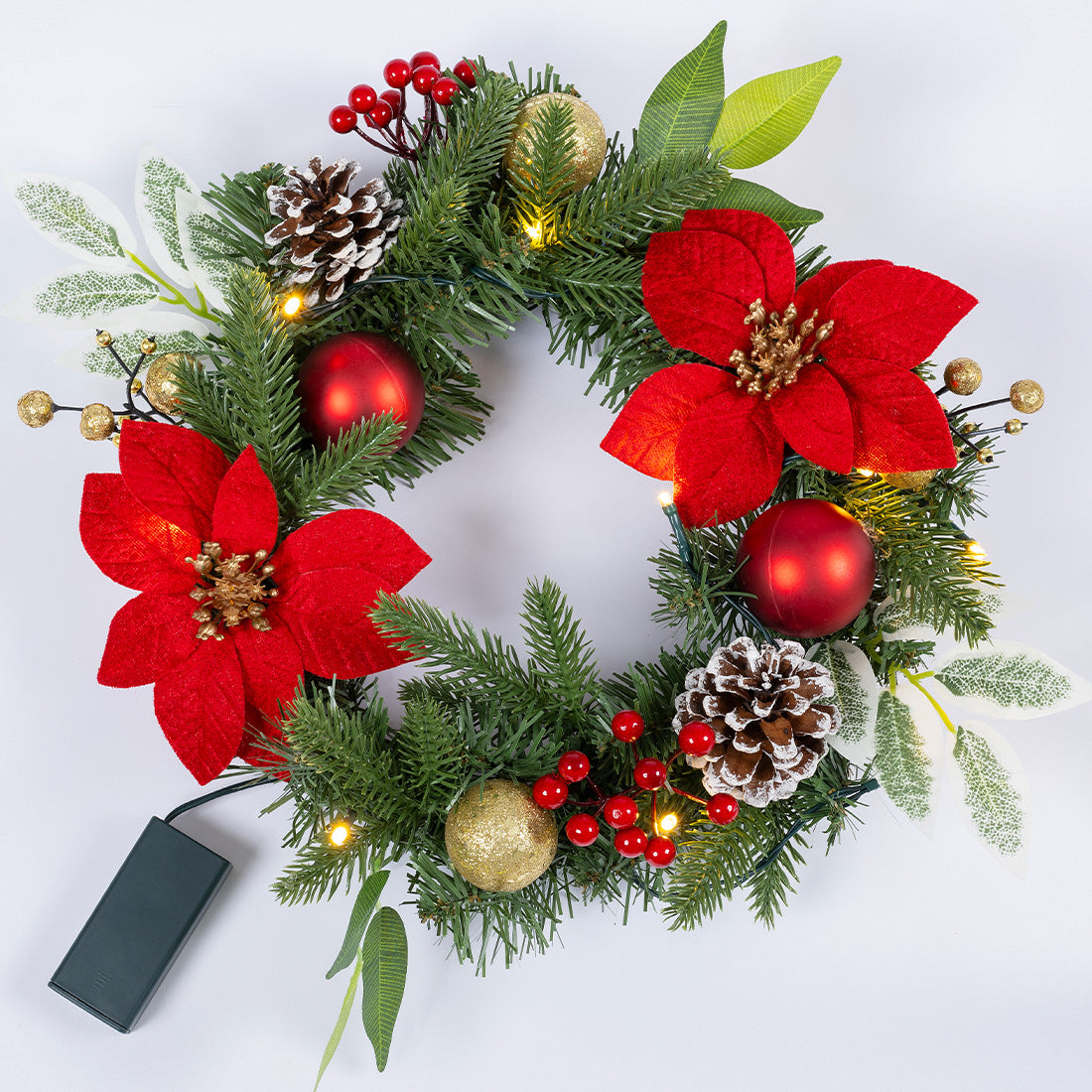 Beleuchteter Weihnachtskranz mit roten Blüten, Tannenzweigen, Kugeln, Zapfen und Batteriefach.