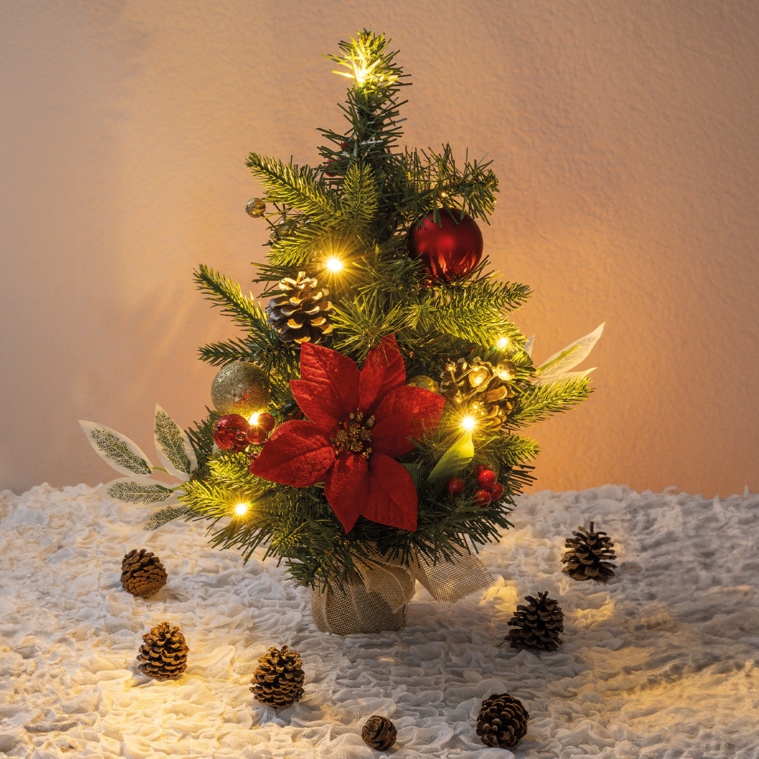 Beleuchteter Mini-Weihnachtsbaum mit roten Blüten, Zapfen und Kugeln – festliche Dekoration für jeden Raum.