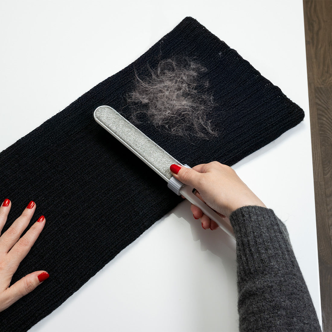Fusselentferner wird auf einem schwarzen Hosenbein angewendet, um Haare zu entfernen