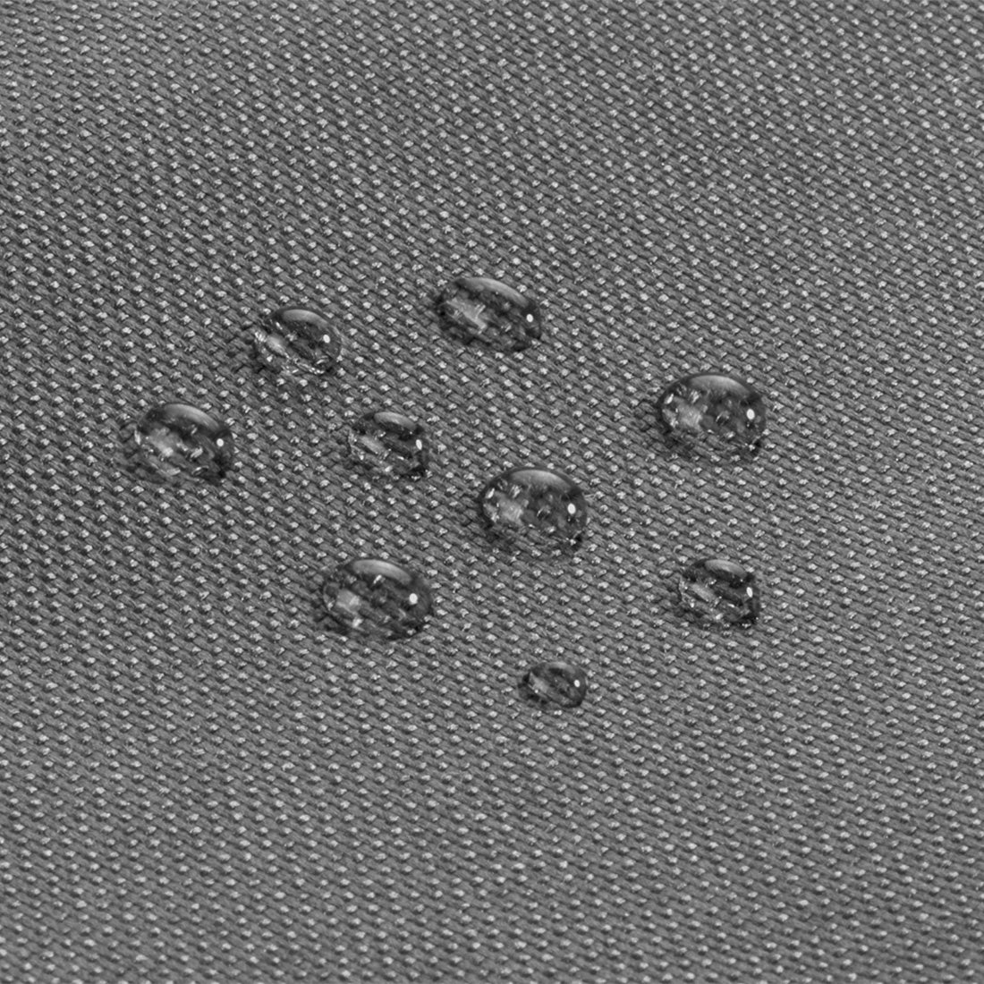 Detailaufnahme eines grauen Textils mit wasserabweisender Oberfläche und sichtbaren Wassertropfen.