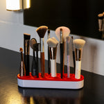 Make-up-Pinsel unterschiedlicher Größe stehen ordentlich in einem rot-weißen Pinselhalter auf dem Waschtisch.