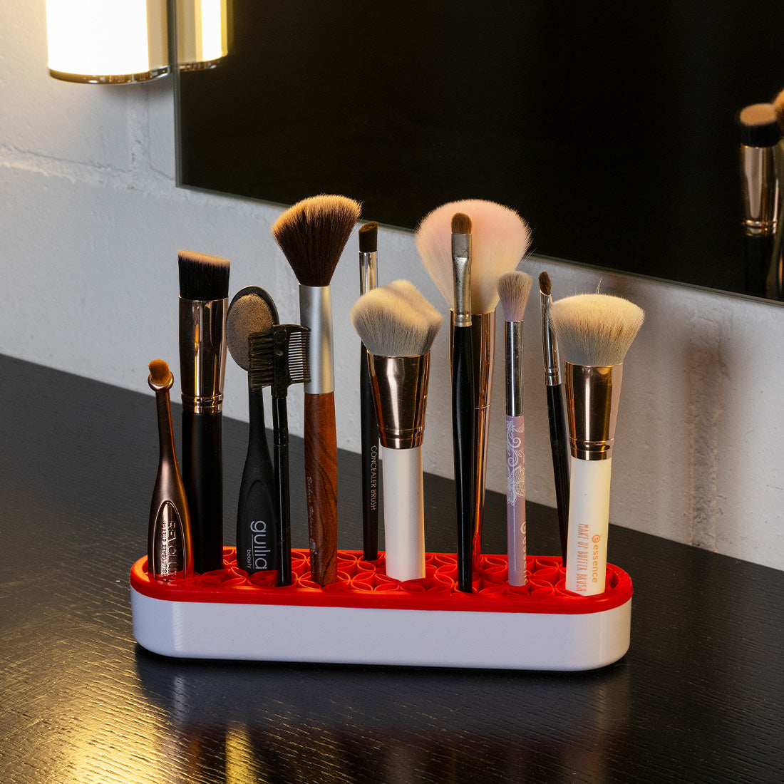 Make-up-Pinsel unterschiedlicher Größe stehen ordentlich in einem rot-weißen Pinselhalter auf dem Waschtisch.