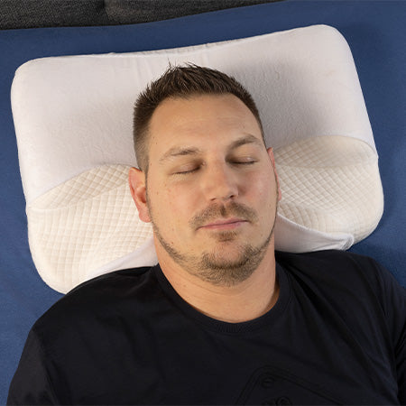 Ein Mann liegt auf dem Rücken auf einem ergonomischen Kissen.