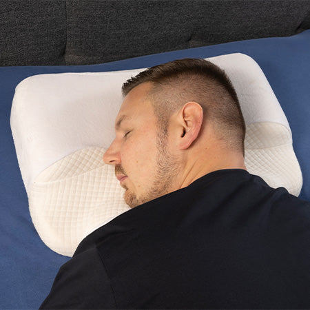Ein Mann schläft auf der Seite auf einem ergonomischen Kissen.