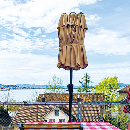 Zusammengeklappter und zusammengebundener Schirm auf Terrasse