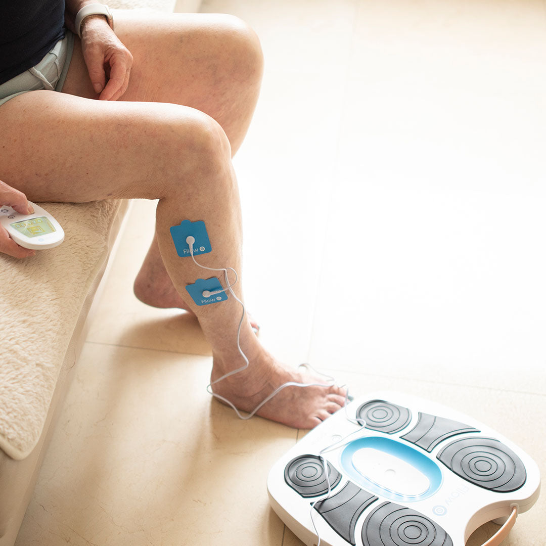 Anwendung des Fllow Stimulations- und Massagegeräts – Elektrodenpads am Bein zur Förderung der Durchblutung und Muskelentspannung.