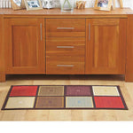 Rechteckiger Patchwork-Teppich mit bunten Quadraten liegt vor einer Holzkommode.