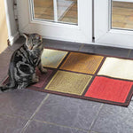 Katze sitzt auf einem bunten Patchwork-Teppich vor einer verglasten Terrassentür.